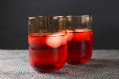 Photo of Delicious cocktails with strawberries and ice balls on grey table