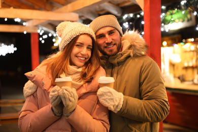 Happy couple with drinks at Christmas fair