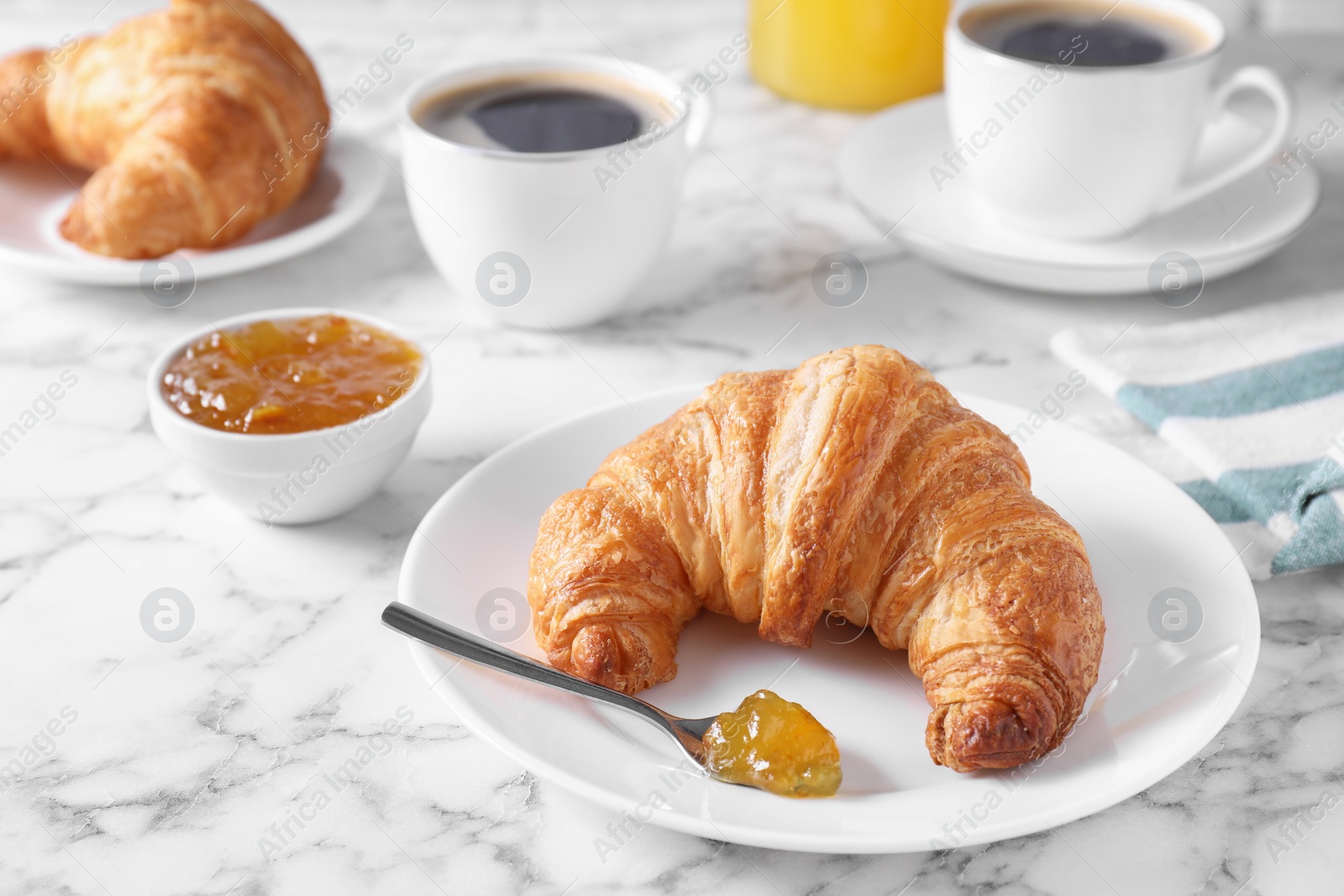 Photo of Tasty breakfast. Fresh croissant and jam on white marble table