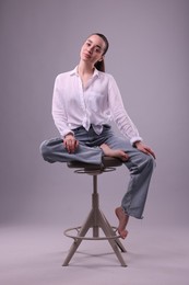 Photo of Portrait of beautiful young woman sitting on chair against light grey background