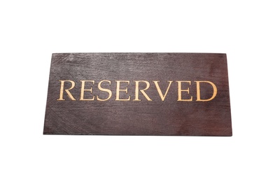 Photo of Elegant wooden sign RESERVED on white background. Table setting element