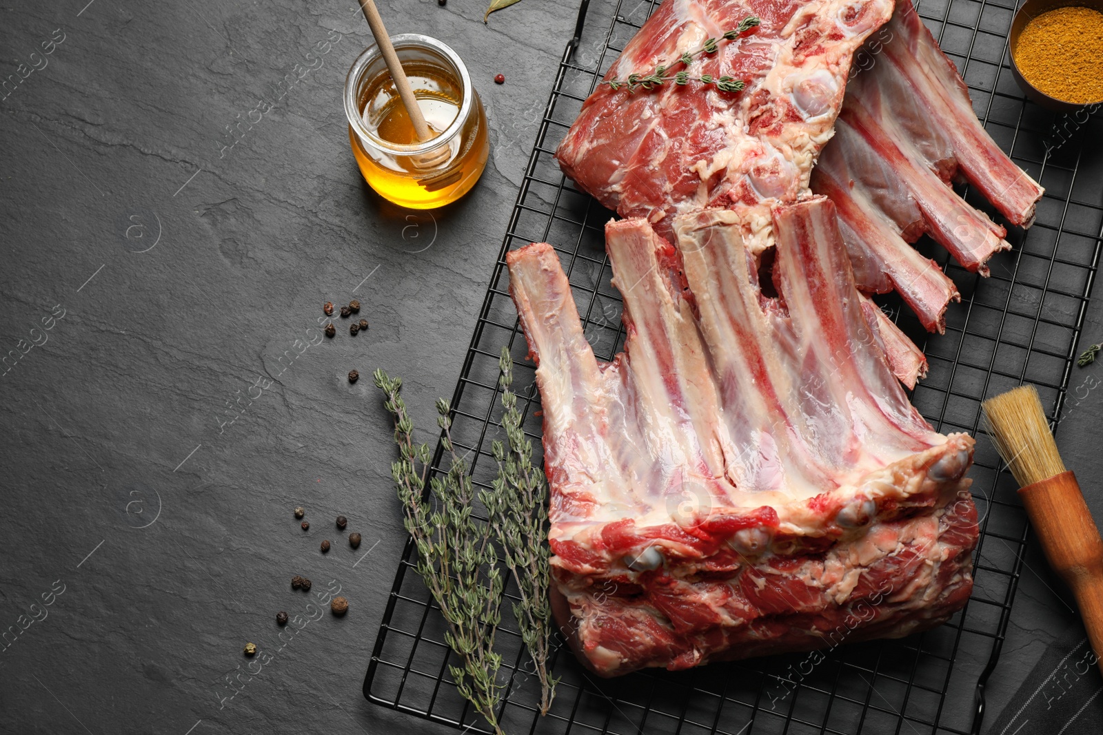Photo of Raw ribs with thyme and pepper on black table, flat lay