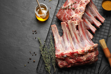 Raw ribs with thyme and pepper on black table, flat lay