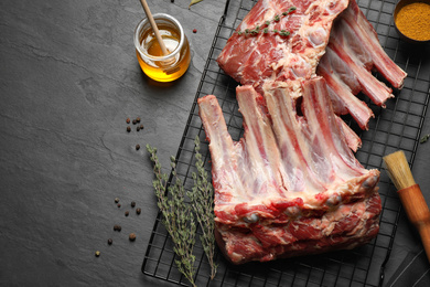 Photo of Raw ribs with thyme and pepper on black table, flat lay