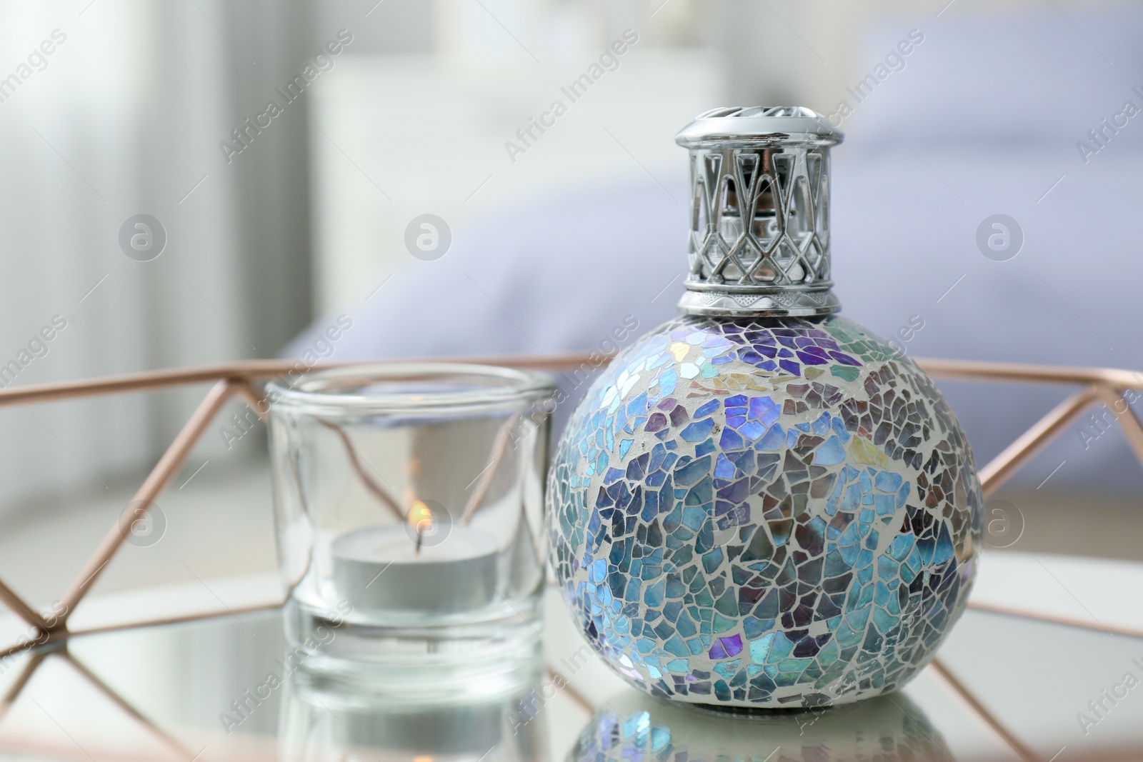 Photo of Stylish catalytic lamp with burning candle on tray in bedroom, closeup. Cozy interior