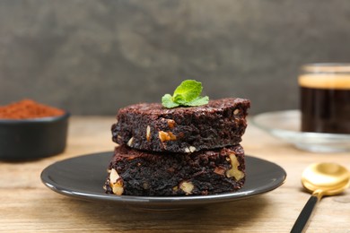 Delicious brownies with nuts and mint on wooden table