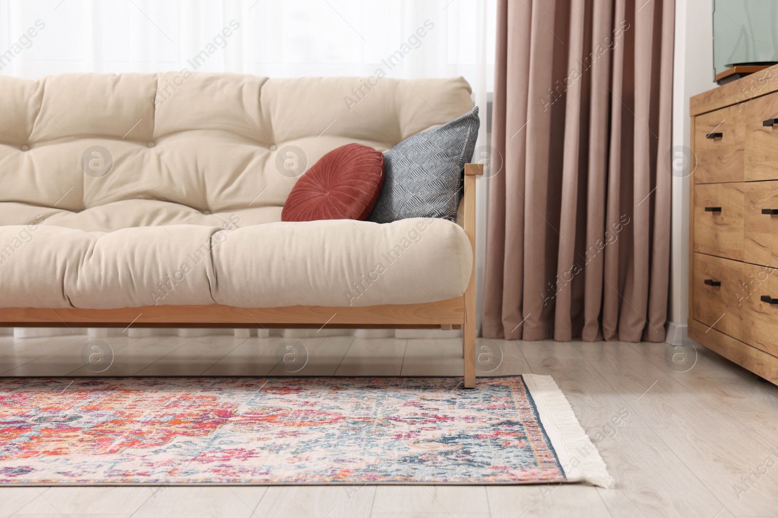 Photo of Beautiful rug, sofa and chest of drawers indoors