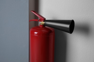 Photo of Fire extinguisher near light wall indoors, closeup