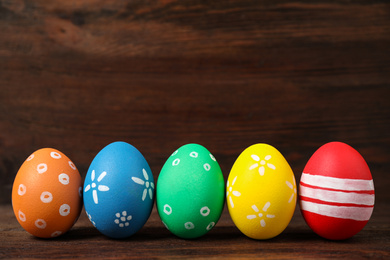 Photo of Colorful Easter eggs on wooden background. Space for text