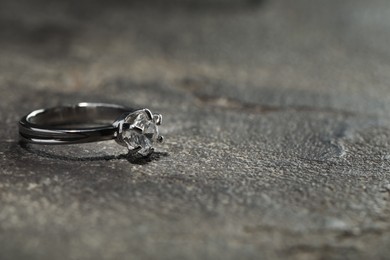 Photo of Beautiful engagement ring with gemstone on grey table, closeup. Space for text