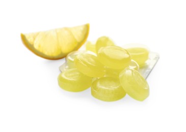 Photo of Many yellow cough drops and slice of lemon on white background