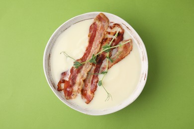 Delicious potato soup with bacon and microgreens on green background, top view