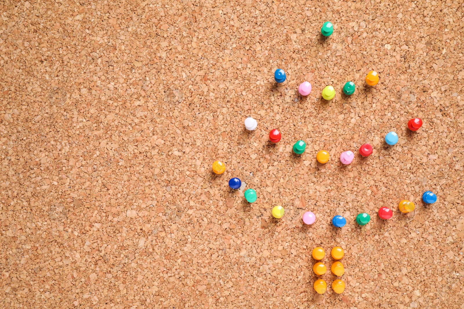 Photo of Christmas tree made with colorful pins on corkboard. Space for text