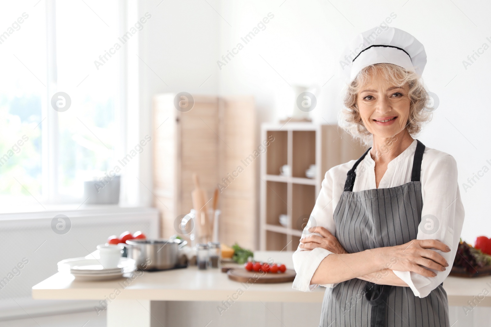 Photo of Professional female chef standing near table in kitchen