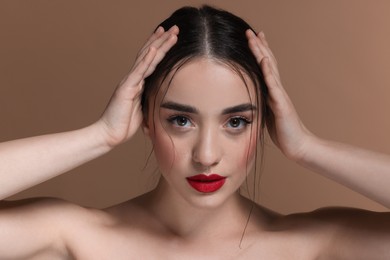 Portrait of beautiful young woman with red lips on brown background, closeup