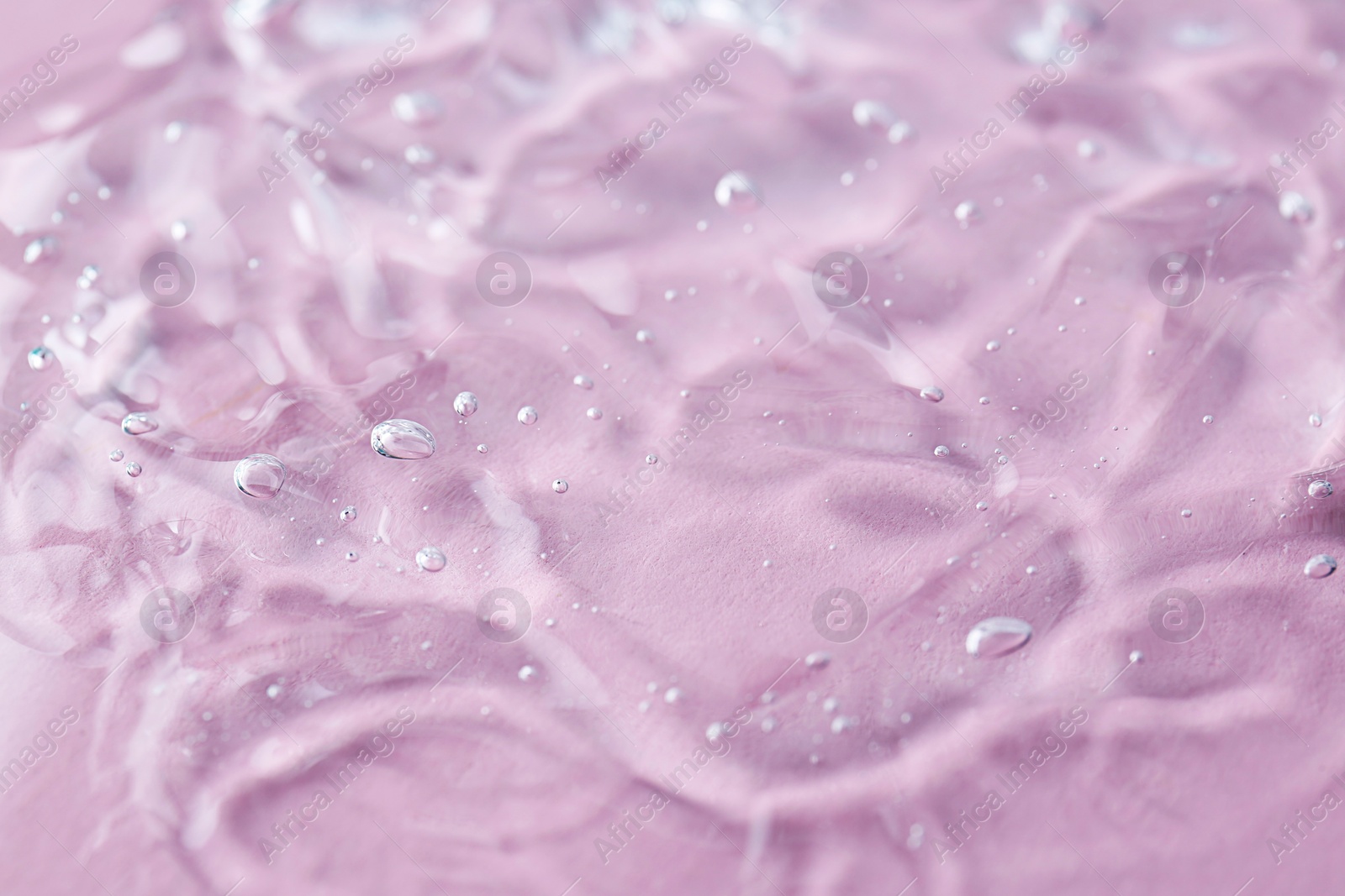 Photo of Texture of transparent shower gel on pink background, closeup