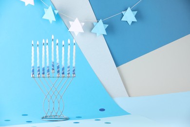 Photo of Hanukkah celebration. Menorah with burning candles on color background, space for text