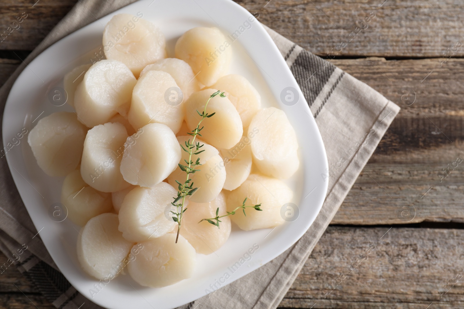 Photo of Fresh raw scallops and thyme on wooden table, top view. Space for text