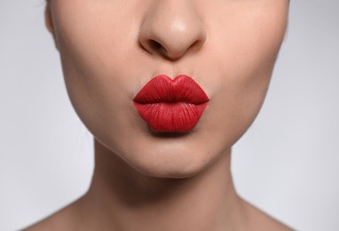 Young woman with beautiful lips makeup on light background, closeup