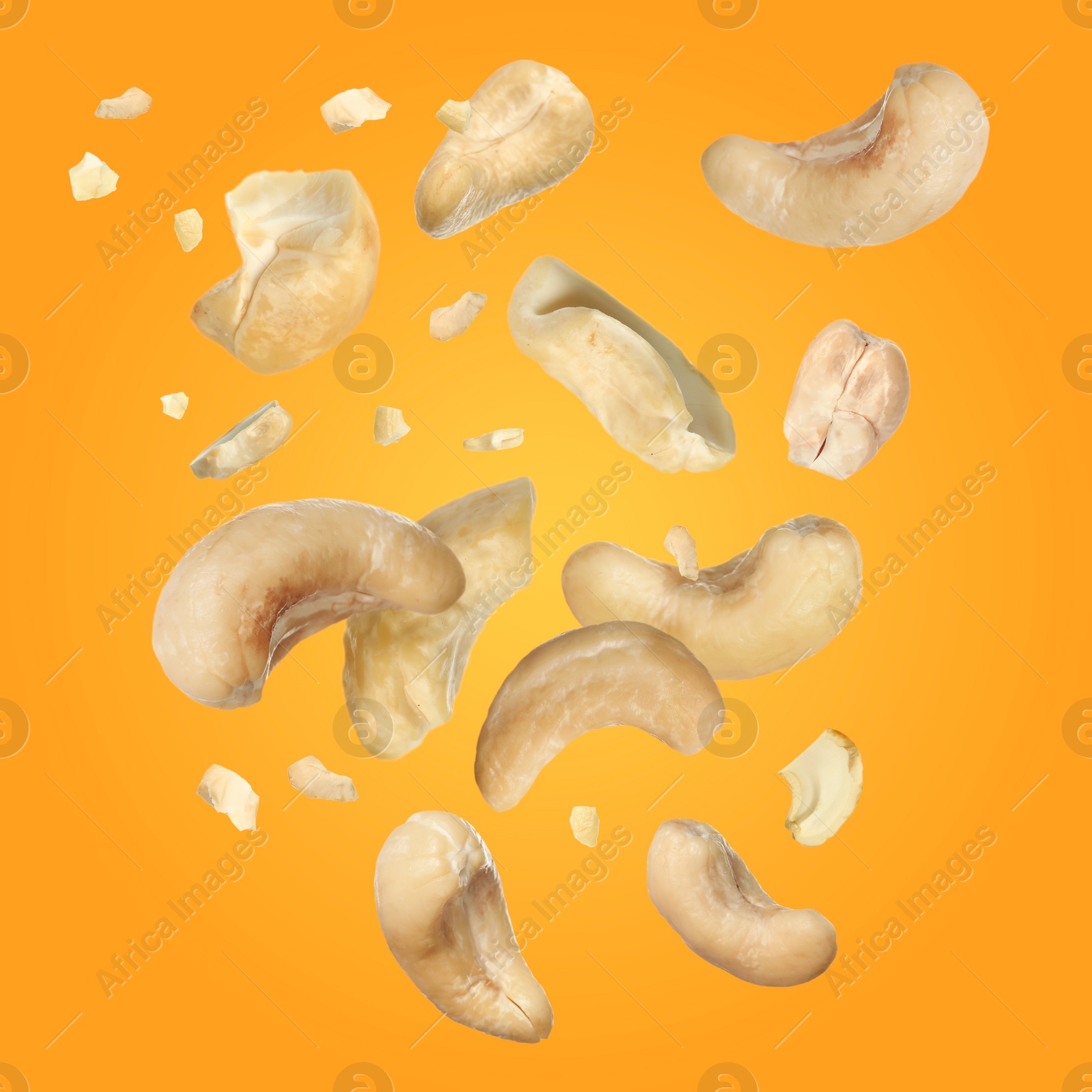 Image of Tasty cashew nuts flying on yellow background