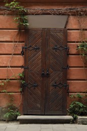 View of building with vintage wooden door and climbing plant. Exterior design