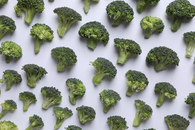 Photo of Many fresh green broccoli pieces on white background, flat lay