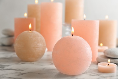 Composition of burning candles and spa stones on table. Space for text