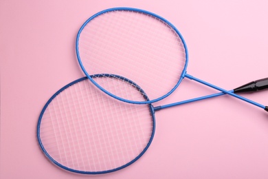 Badminton rackets on pink background, flat lay