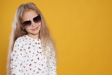 Photo of Girl wearing stylish sunglasses on orange background, space for text