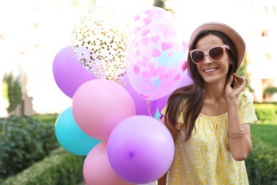 Photo of Cheerful young woman with color balloons in park