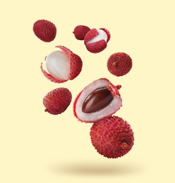 Many fresh lychees falling on beige background