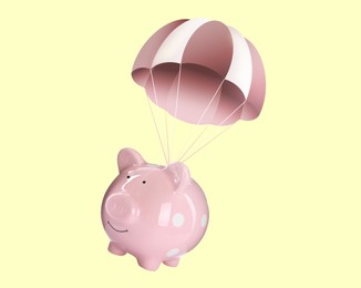 Image of Pink piggy bank with parachute flying on beige background