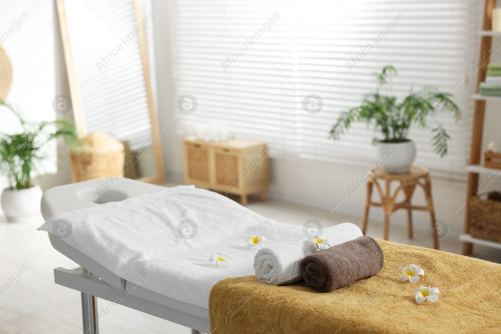 Photo of Massage table with towels and flowers in spa center