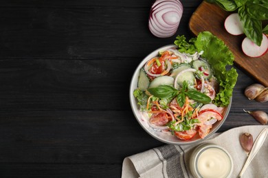 Bowl of delicious vegetable salad dressed with mayonnaise and ingredients on black wooden table, flat lay. Space for text