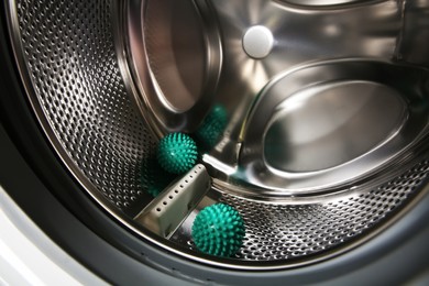 Photo of Green dryer balls in washing machine drum, closeup