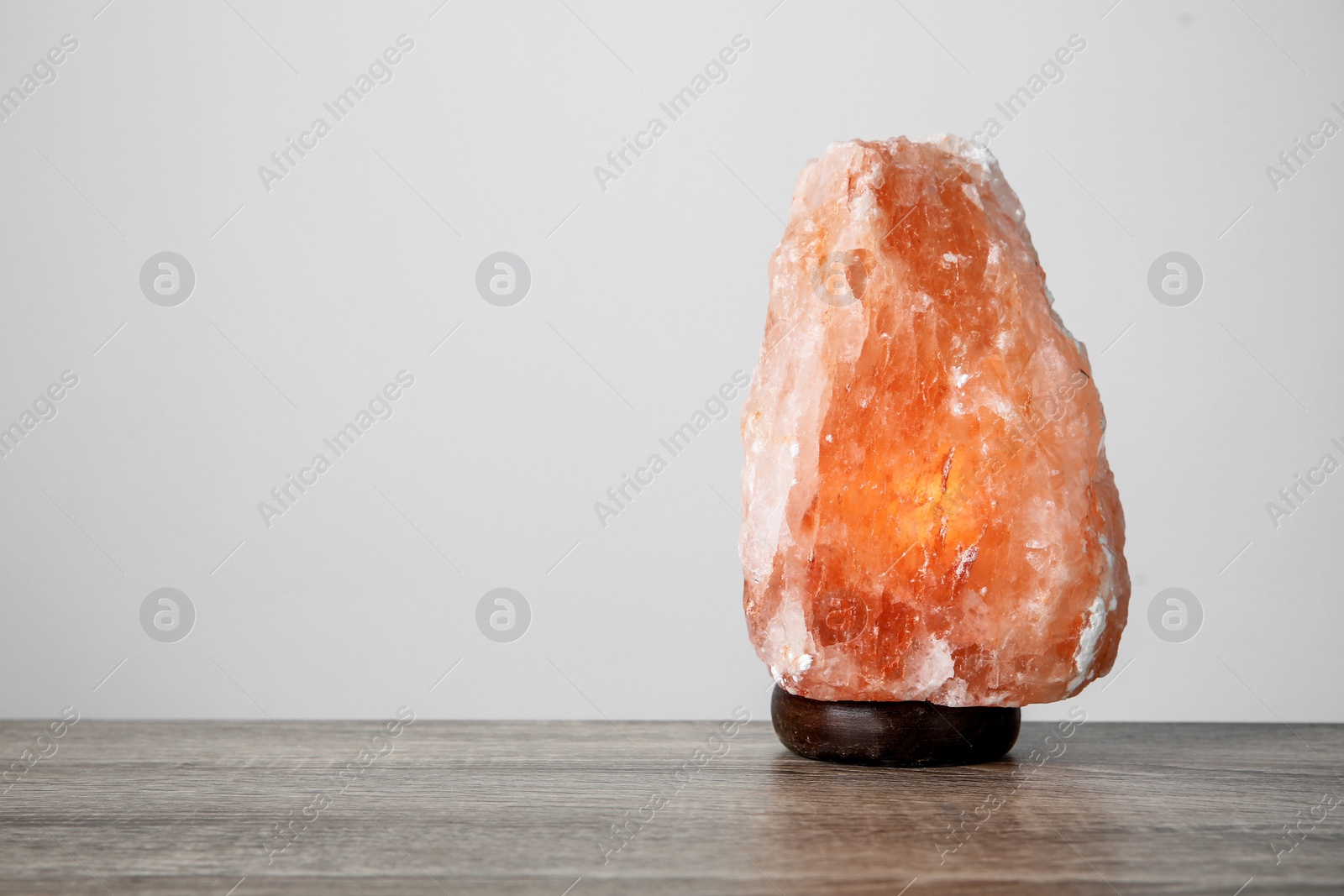 Photo of Himalayan salt lamp on table against light background