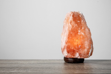 Himalayan salt lamp on table against light background