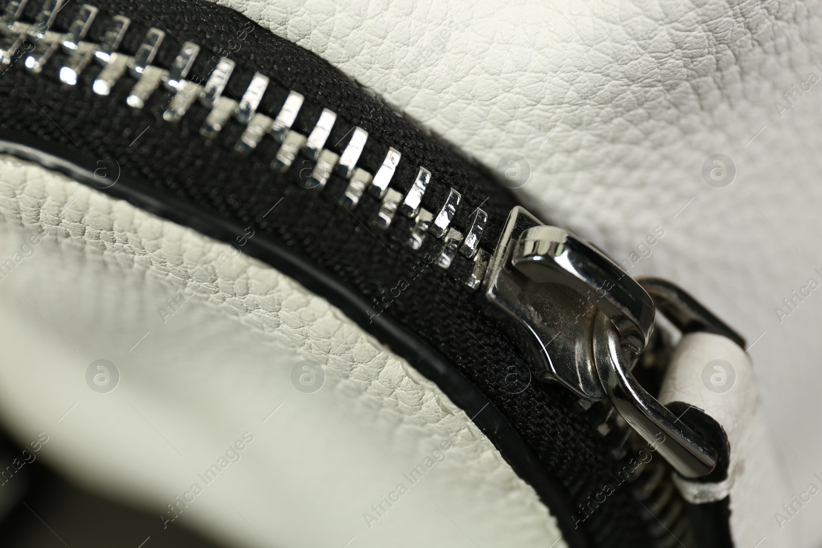 Photo of White leather fabric with zipper as background, closeup view