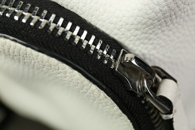 Photo of White leather fabric with zipper as background, closeup view