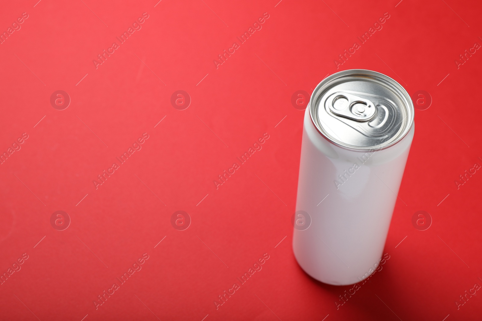 Photo of White can of energy drink on red background. Space for text