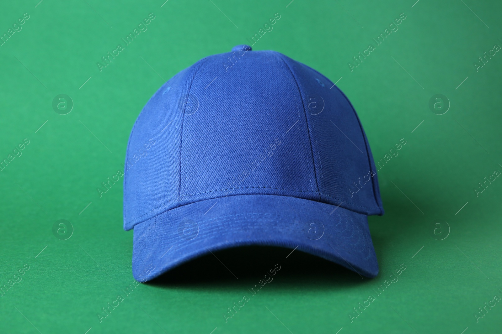 Photo of Stylish blue baseball cap on green background