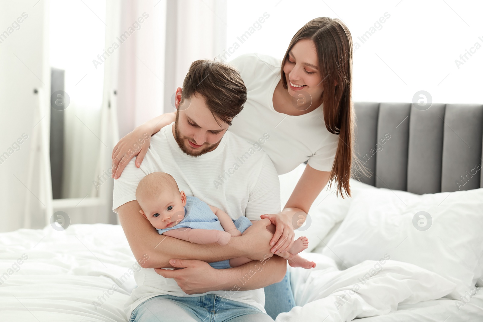 Photo of Happy family. Parents with their cute baby on bed indoors