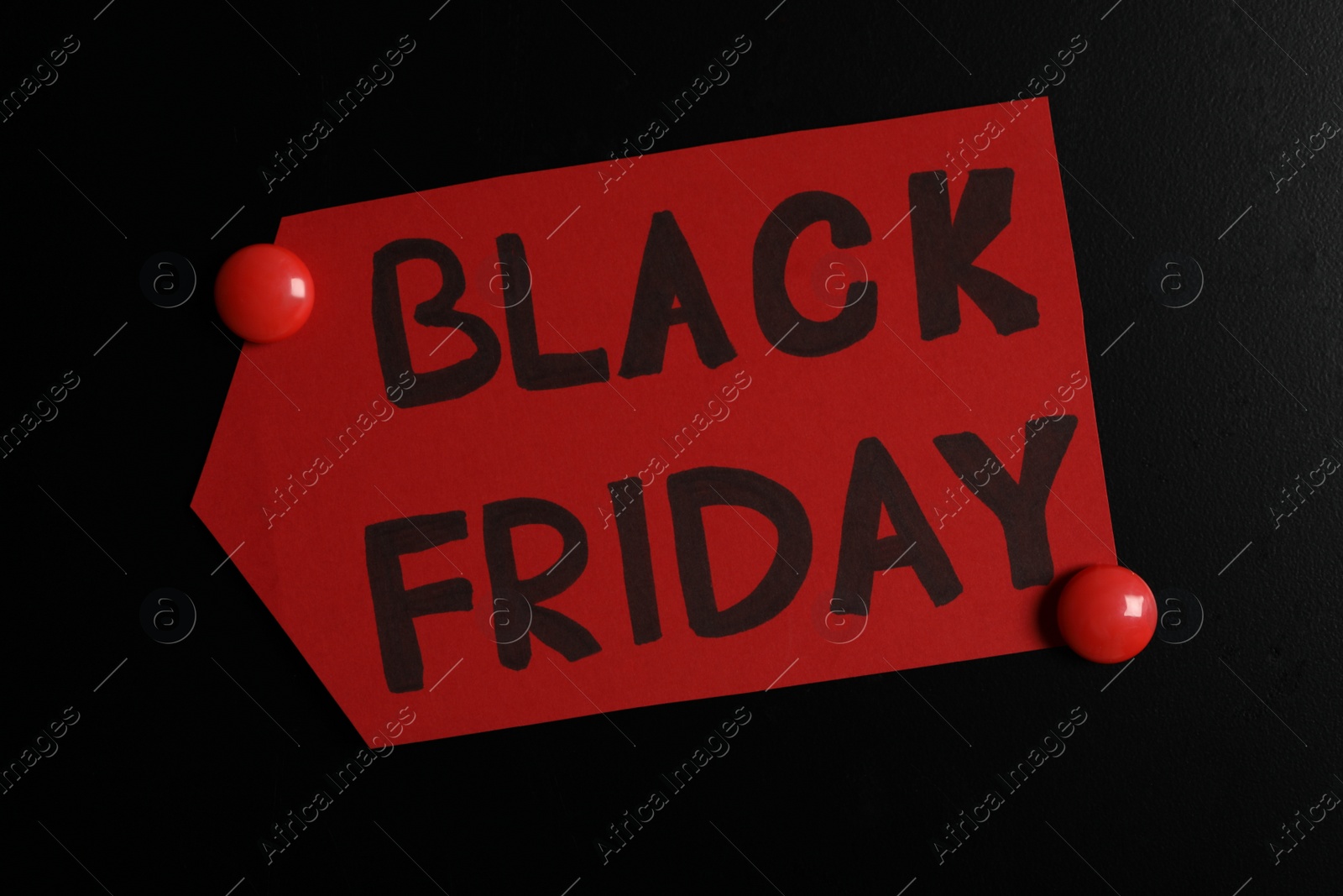 Photo of Tag with phrase Black Friday on dark background, top view