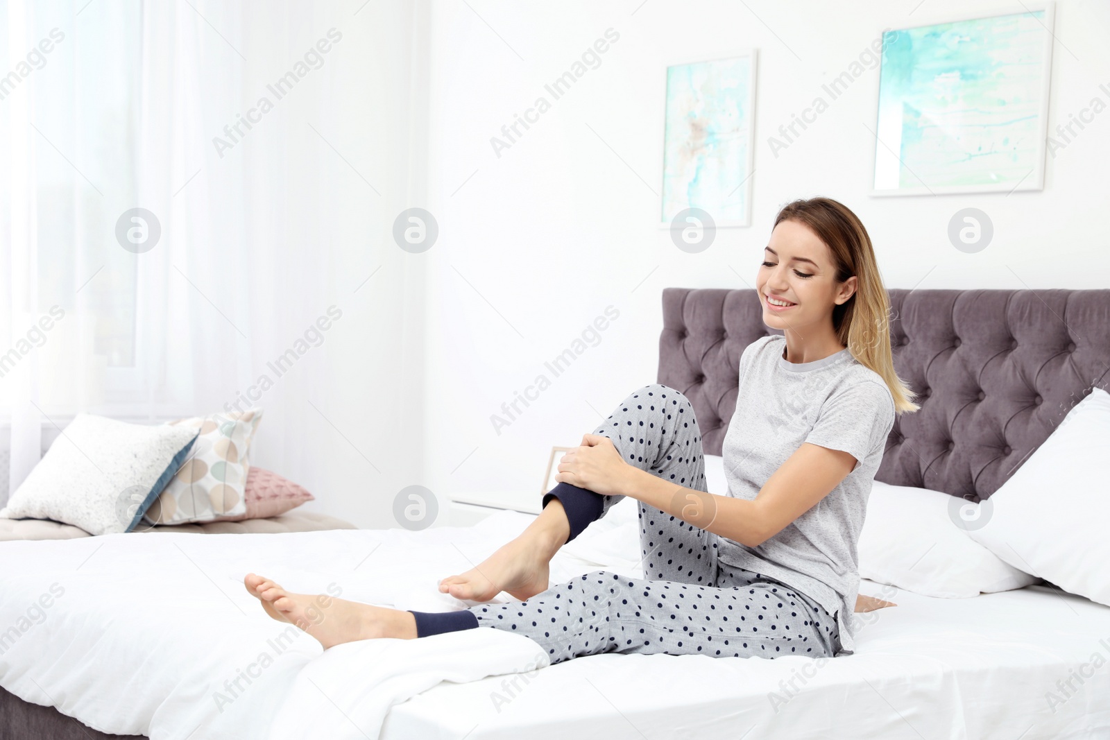 Photo of Young beautiful woman doing exercise on bed at home. Morning fitness