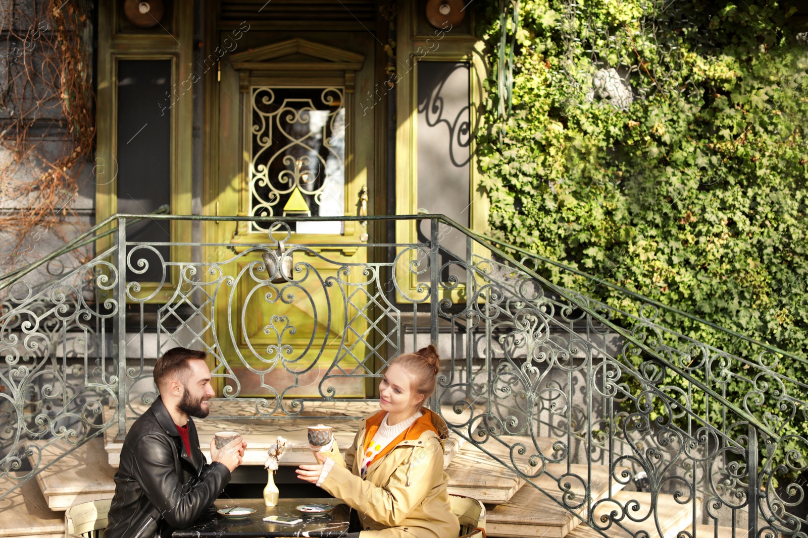 Photo of Lovely young couple enjoying tasty coffee at outdoor cafe