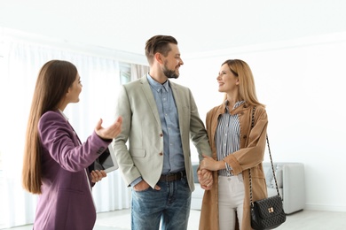 Female real estate agent showing new house to couple, indoors