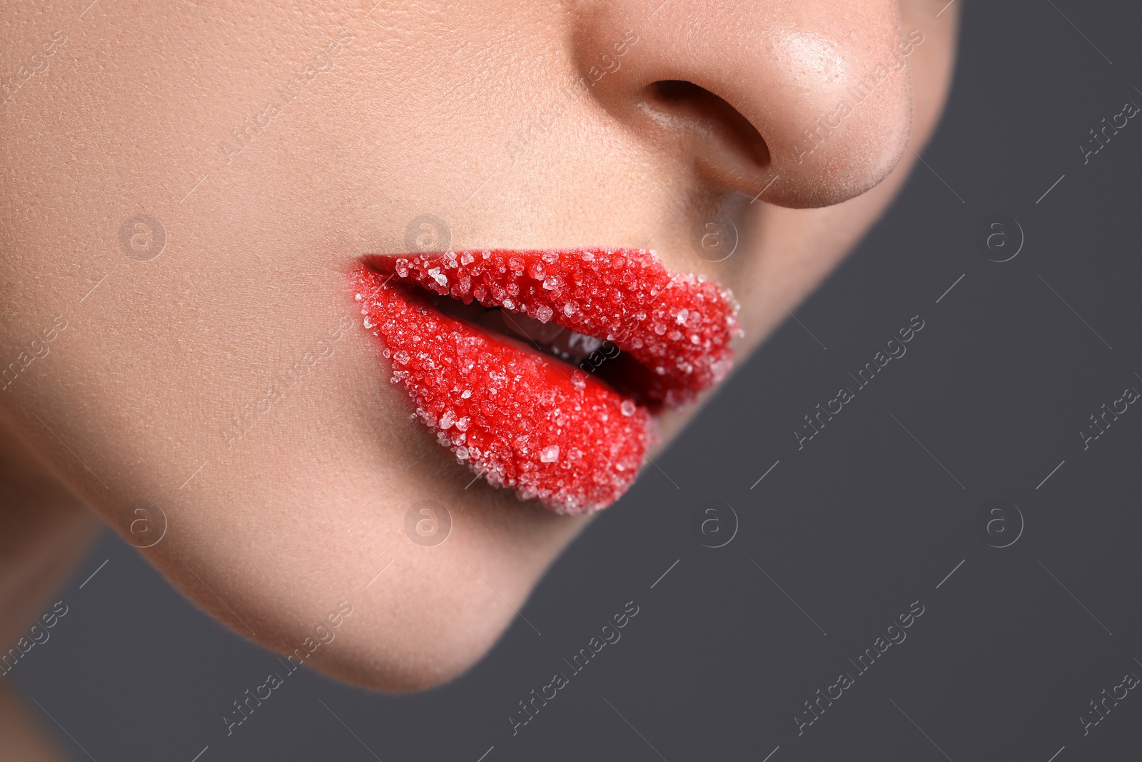 Photo of Woman with beautiful lips covered in sugar on grey background, closeup