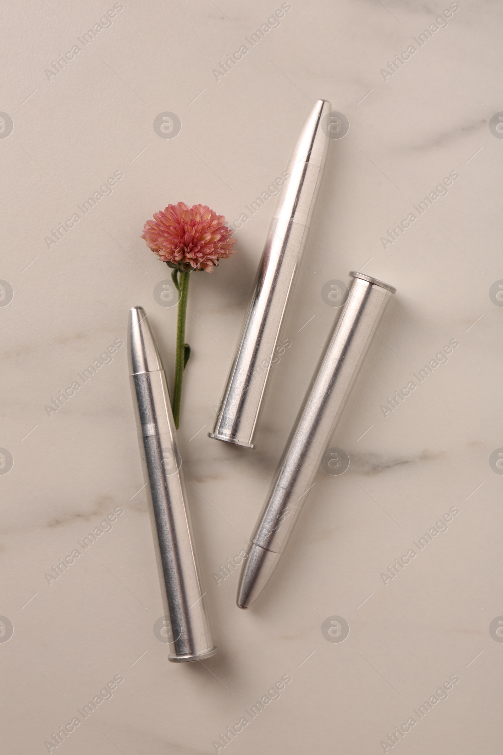 Photo of Bullets and beautiful flower on light marble table, flat lay