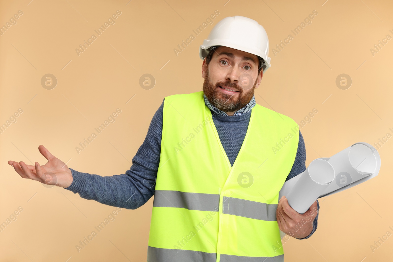 Photo of Confused architect in hard hat with drafts on beige background