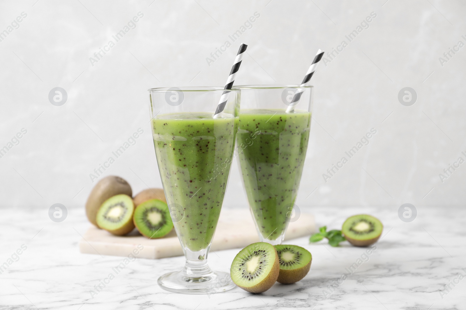 Photo of Delicious kiwi smoothie and fresh fruits on white marble table